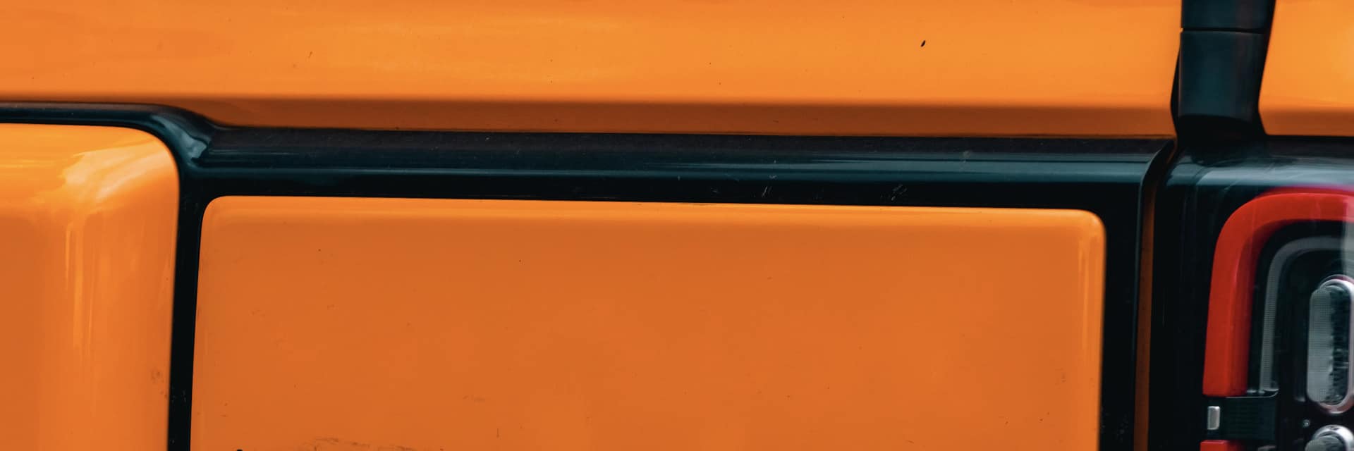 A bright orange '100% electric' badge on the side of a vehicle