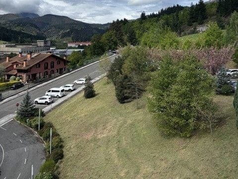 A road and red-roofed houses of Arrasate-Mondragón surrounded by green wooded hills
