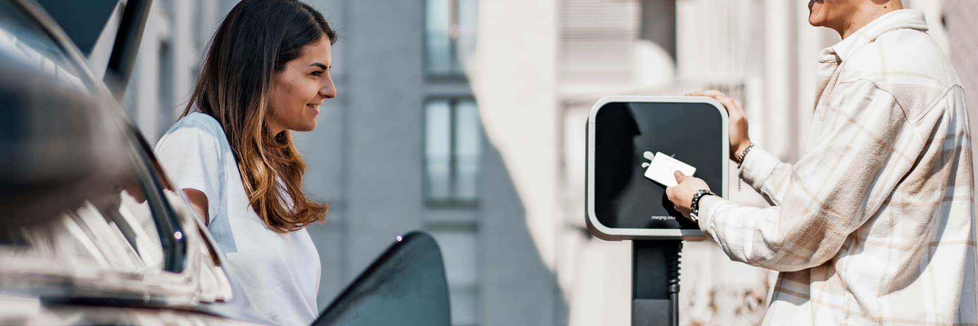 Two people chatting while charging an electric car