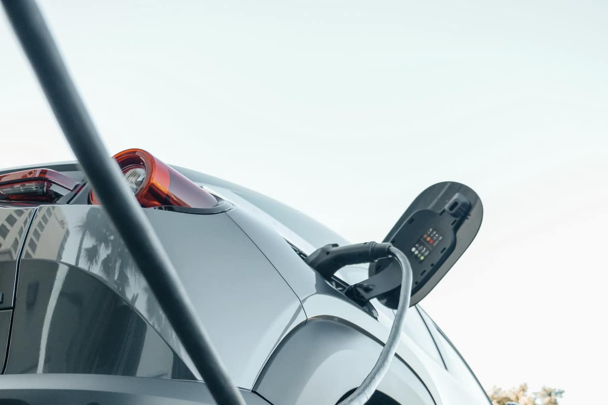 An electric car charging at dusk, seen from the rear