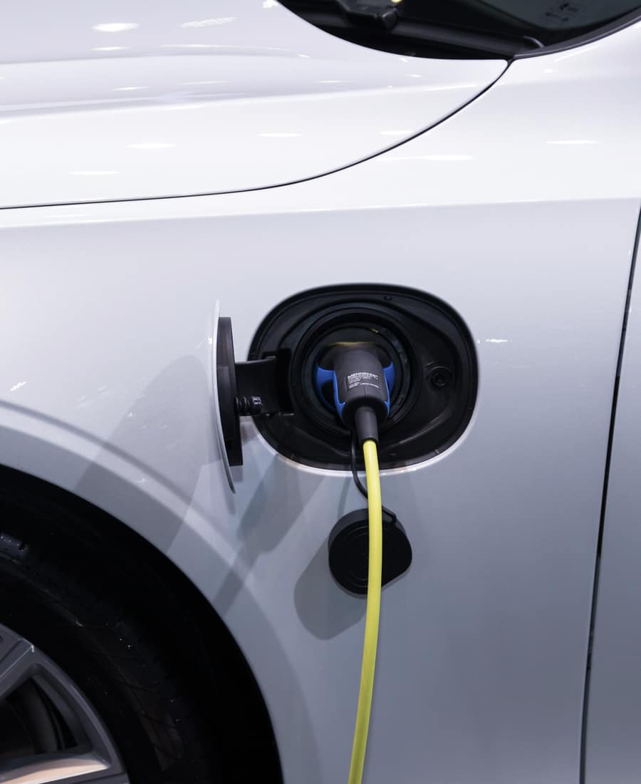 Close-up of a charging cable running to an electric car's wheel arch