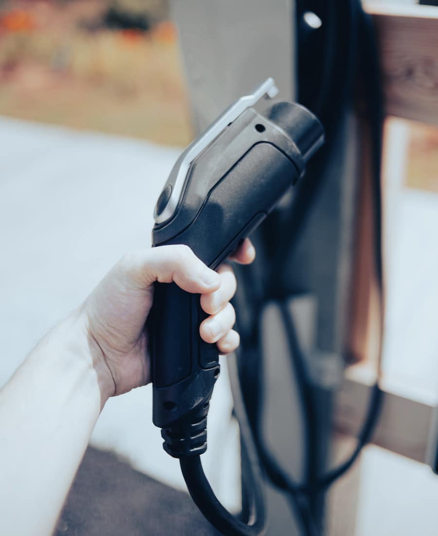 A hand holding an EV charging connector, ready to plug in